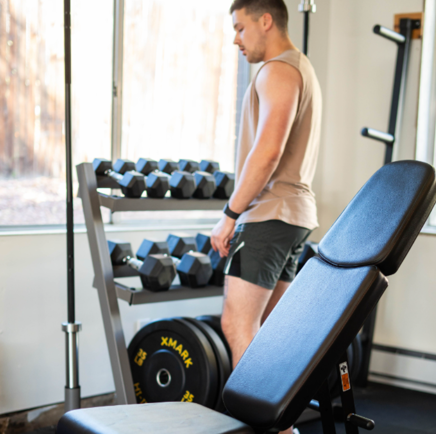 Man in workout clothes standing in front of dumbbell rack