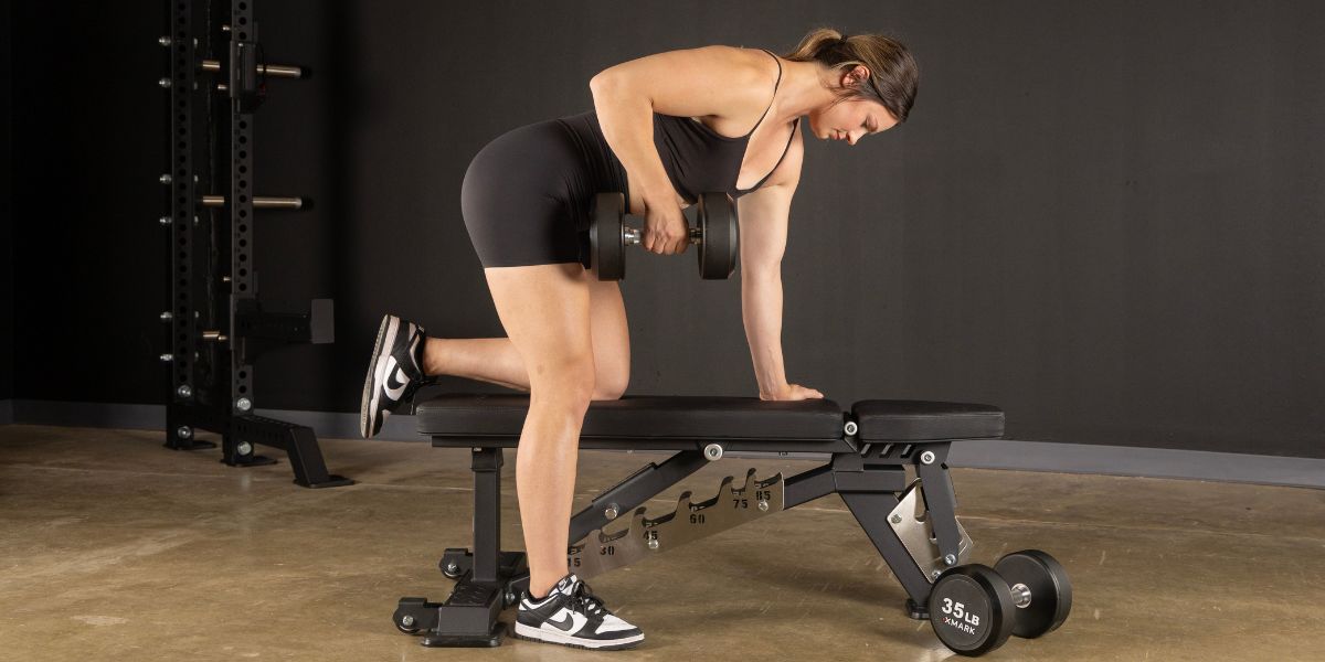 Woman on an XMARK bench doing dumbbell rows 