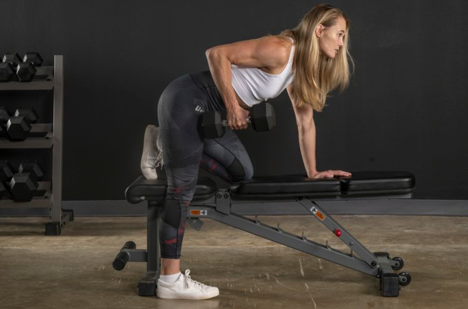 Woman performing single arm row on bench