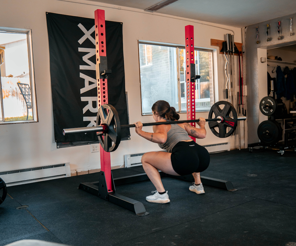 Female performing back squat in rack with barbell