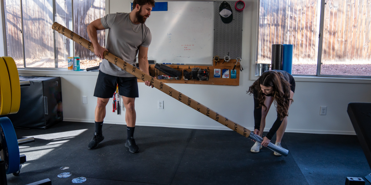 man and woman using barbell