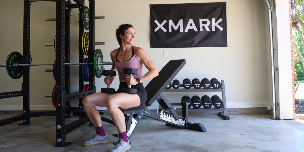 woman using adjustable bench to workout with dumbbells in a garage