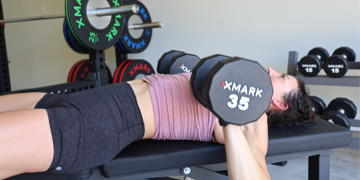 woman doing bench press with dumbbells