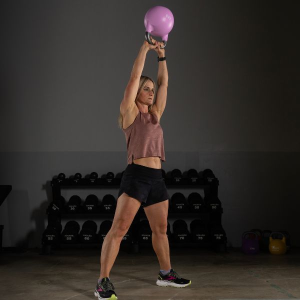 Woman performing kettlebell swings with a purple kettlebell