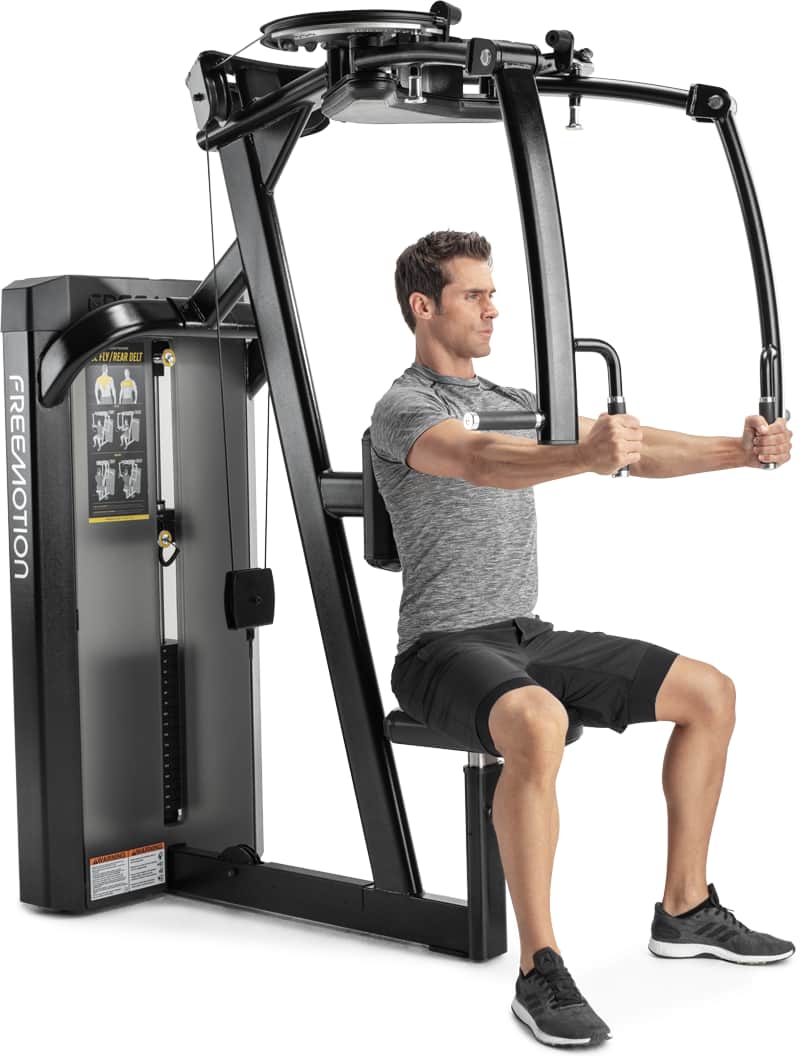 A man seated on a Freemotion chest press machine, demonstrating use of the exercise equipment.