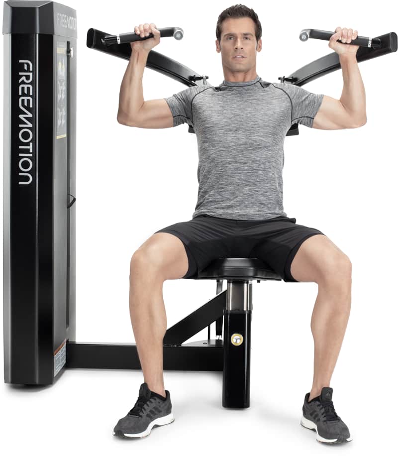 A man seated on a Freemotion overhead press machine.