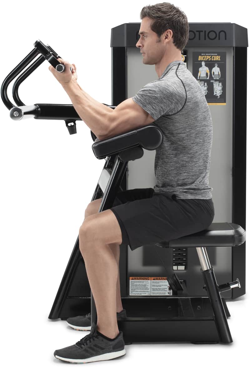 A man exercising on a Freemotion biceps curl machine.