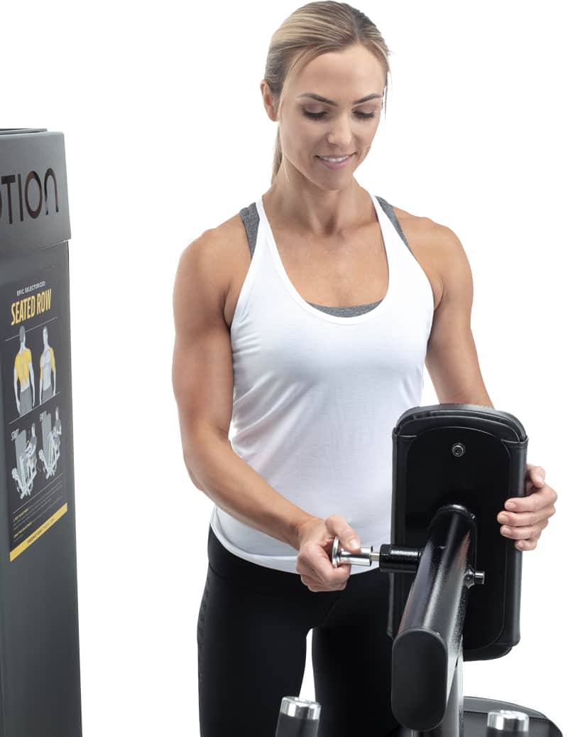 A woman adjusting the chest page on a A Freemotion seated row machine