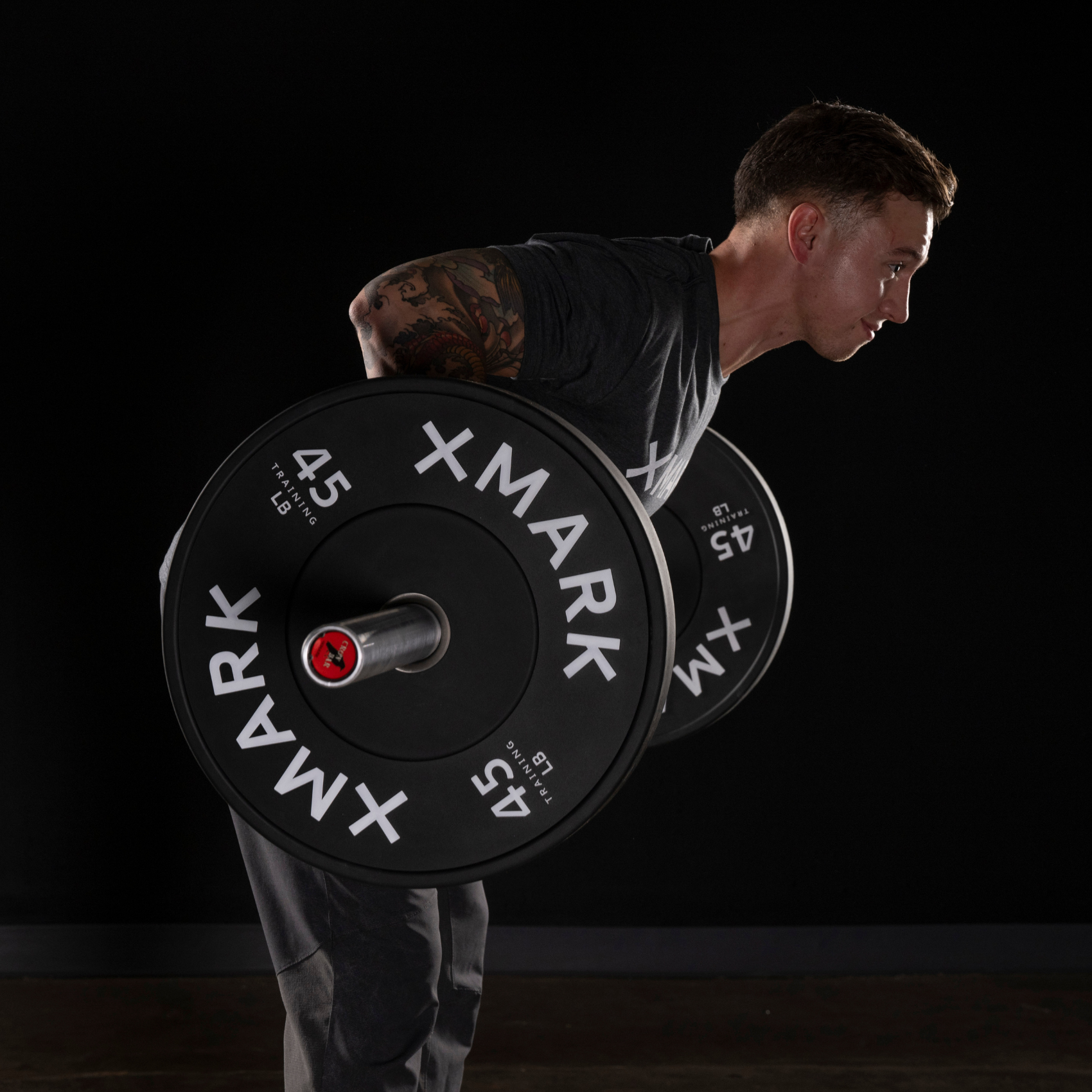 MAN DOING A BARBELL ROW WITH XMARK OLYMPIC BAR AND BUMPER PLATES 