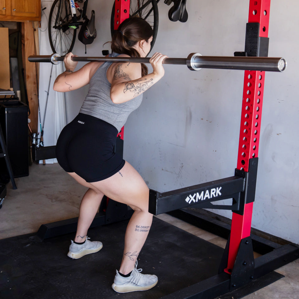 woman back squatting with barbell inside squat rack